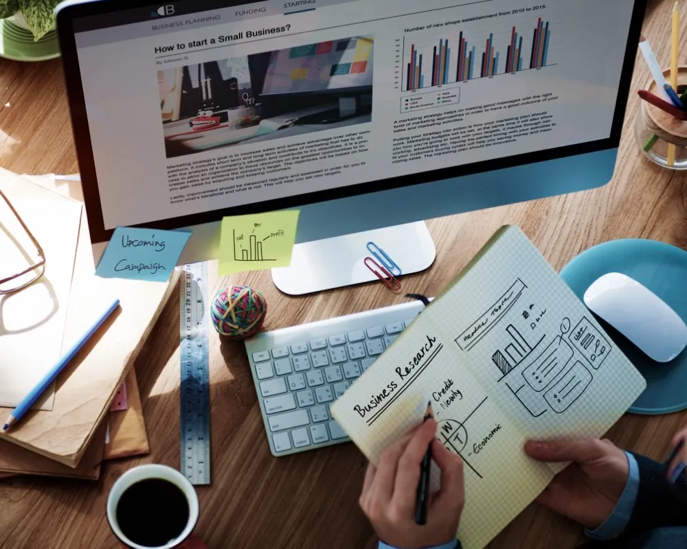 Foto de hombre en oficina con computador, elementos de oficina y cuaderno planeando estrategias para la agencia SEO TexMex