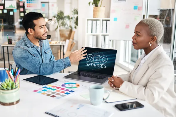 Dos colegas discuten los servicios SEO que impactan directamente en el posicionamiento web de su empresa.